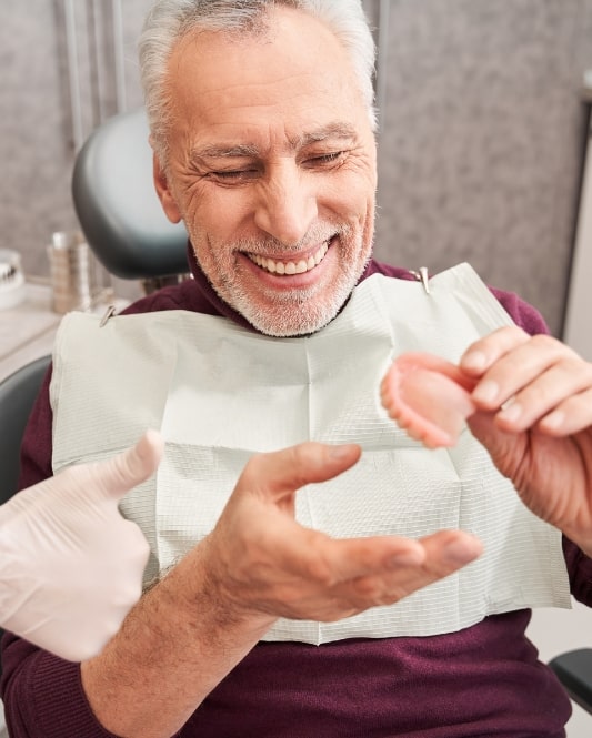 denture patient happy looking at dentures